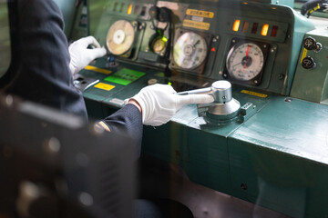 Action of train driver is controlling the accelerator lever to speed up the train. Transportation working scene photo, selective focus at human hand.