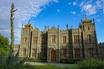 Fototapeta premium Vorontsov Palace in Crimea in summer. Ancient walls with many columns, turrets and domes. An architectural masterpiece, the legacy of the ancestors. Green trimmed bushes