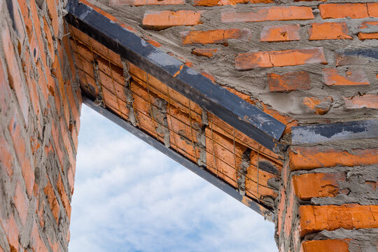 Window, door metal lintel with iron bar on brick unfinished building house construction.