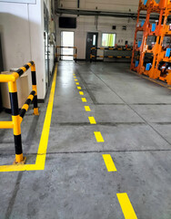 Industrial building corridor painted yellow between parallel yellow lines on abstract cement...