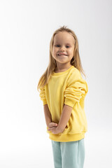 Fototapeta premium Portrait of beautiful cute little toddler girl. Child with funny face in yellow sweatshirt jumps. Pretty smile kid in studio on white background. High quality photo
