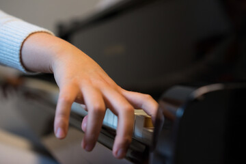 Human hands playing the keys notes and chords on a classic black piano during a pianolesson