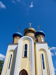 Three domes with crosses (one golden and two blue) of the Orthodox Church, blue sky.