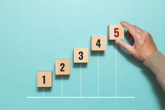 A man hand place wooden cubes with number five for rating. Priority of activities. Concept of task priority and management