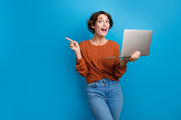 Photo portrait of pretty young girl hold netbook point look excited empty space wear trendy brown...