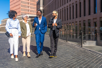 Fototapeta premium Multi-ethnic business people walking relaxed during a coffee break outdoors
