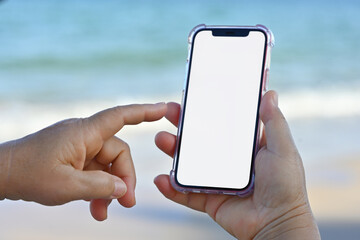 Close-up of an elderly woman's hand holding a mobile phone with an empty screen for text and design against the blue sea