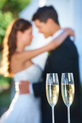 Champagne, happy couple and blurred embrace at wedding with love, smile and commitment at reception. Wine glasses, woman and man hugging at marriage celebration event, partnership and future together