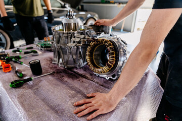 Mechanic checking engine. Disassembled electric car engine. Partially disassembled for repair motor...