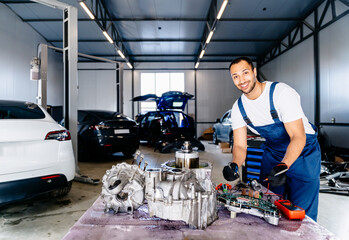 Electric car engine removed from car for repair. Arabian man use voltmeter working Internal...