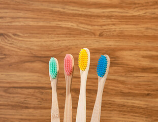 Ecological toothbrushes with bright colorful bristles on a wooden background. Care health.