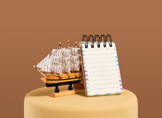 Small ringed notebook and decorative ship. Composition with school or office stationery.