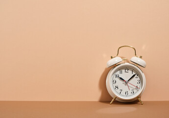 White retro alarm clock on a beige background. Time to wake up.