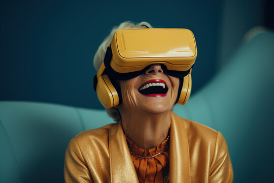 Laughing cheerful middle aged woman using virtual reality helmet while sitting indoors, modern positive senior woman wearing VR glasses. - Powered by Adobe