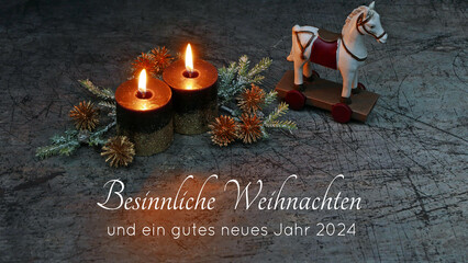 Weihnachtskarte: Nostalgische Weihnachtsdekoration mit zwei brennende Kerzen, Tannenzweigen,Schaukelpferd und dem Text Besinnliche Weihnachten und ein gutes neues Jahr 2024.	