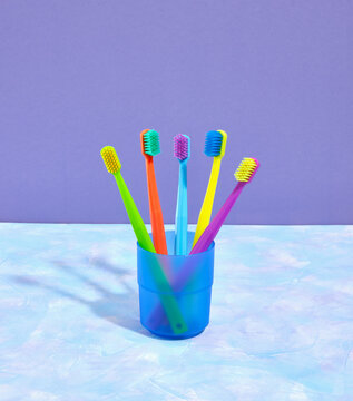 A composition of colored toothbrushes in a blue glass. Personal hygiene. Home dental care.
