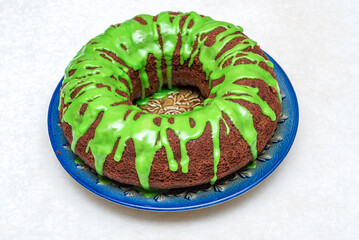 Homemade round cupcake with green frosting on a blue plate.