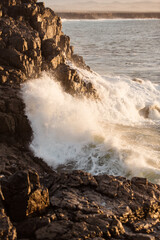 Stunning images of waves crushing into the ancient volcanic stones on shore at sunset in Fuerteventura island Spain