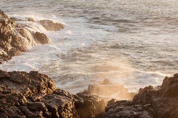 Stunning images of waves crushing into the ancient volcanic stones on shore at sunset in Fuerteventura island Spain
