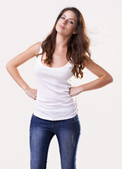 Portrait, fashion or casual and a woman in studio on a white background with her hands on her hips. Trendy, style and clothes with a confident young female model in a denim jeans and tank top outfit