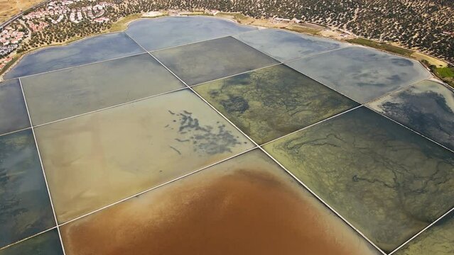Aerial wide shot of coastal saltern with evaporation ponds saltworks