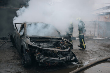 Firefighters extinguish a burning car on the street. Burnt car. Rescuers. Strong smoke. Emergency....