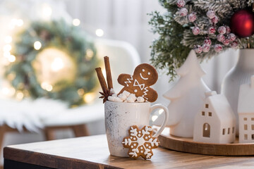 Homemade Christmas ginger cookies in powdered sugar. Delicious ginger man in a mug with coffee and marshmallow marshmallows on the background of a bokeh of Christmas tree lights. 
