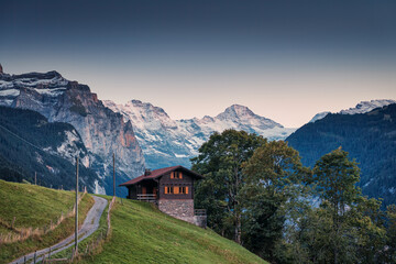 Fototapeta na wymiar View from Wengen mountain village with Jungfrau and wooden cottage on hill in the evening at Switzerland
