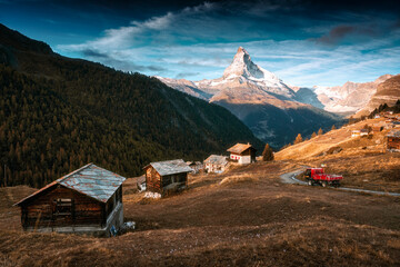 Matterhorn mountain with truck driving on the road and wooden huts on the hill in the morning on...
