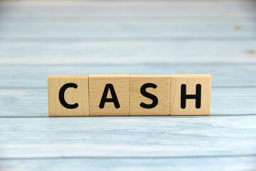 "CASH" text or message short word english letter on wooden cubes block with blue vintage background.Copy space.