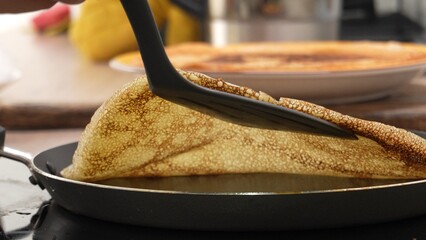 Spatula lifting a pancake, revealing underside texture. The action depicts the turning process...