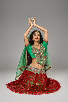 good looking young indian woman in traditional clothes sitting on floor and gesturing with arms