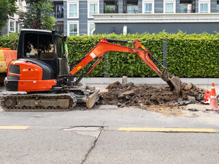 The compact size of the excavator is dismantling the footpath