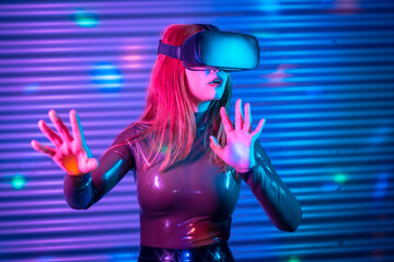 Futuristic amazed woman gesturing while wearing VR goggles
