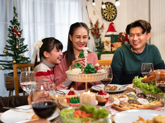 Naklejka premium Happy Asian family mother, father and daughter having dinner celebrating Christmas at home