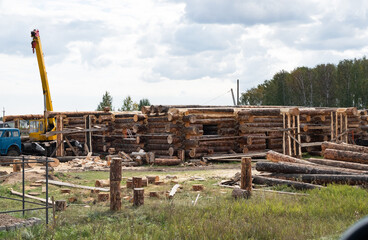 Wooden a log houses under construction with building materials lying nearby