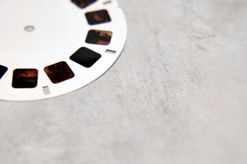 Close-up of a white toy view master slide laying on a grey concrete effect surface with room for...