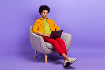 Fototapeta na wymiar Photo of successful man it specialist working sitting armchair furniture isolated on purple color background