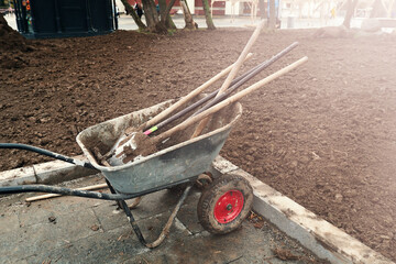 A wheelbarrow with shovels and other tools for cultivating the land.