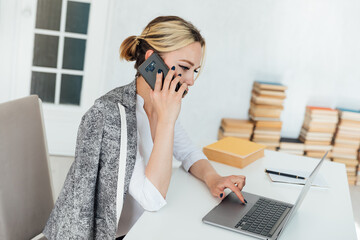 Business woman talking on the phone in the office at the computer