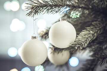 Fototapeta na wymiar Christmas composition. Beautiful white balls on a Christmas tree branch close-up on a sparkling light background
