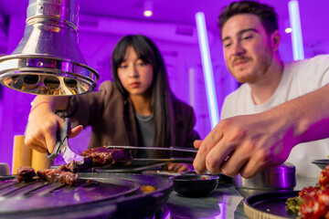 close-up of a couple in love having dinner in a Korean restaurant picking up juicy meat from the...