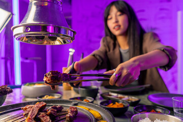 close-up of a couple in love having dinner in a Korean restaurant picking up juicy meat from the...