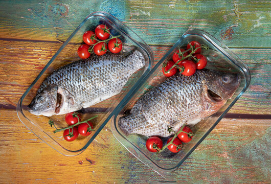 Fresh large dorado fish, tilapia, carp in baking dish with cherry tomatoes, step by step recipe instructions, top view on old green wooden table high quality photo