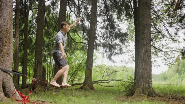 Man walks on taut rope, balancing. Slackline, slinger guy. Perfect hull balancing and control.