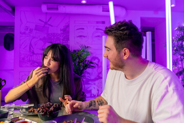 a couple in love in a Korean grill restaurant tastes a variety of traditional dishes with pleasure
