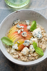 Risotto with pear, blue cheese and green basil leaves in a grey bowl, vertical shot, middle close-up