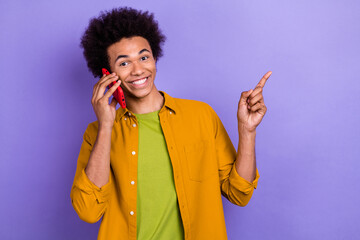 Photo of cheerful nice man wear trendy yellow clothes speaking talking presenting empty space banner isolated on violet color background