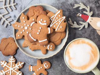 Top view of Christmas cookies in a variety shape as a gingerbread man in a plate decorated with  royal icing with a cup of latte coffee
