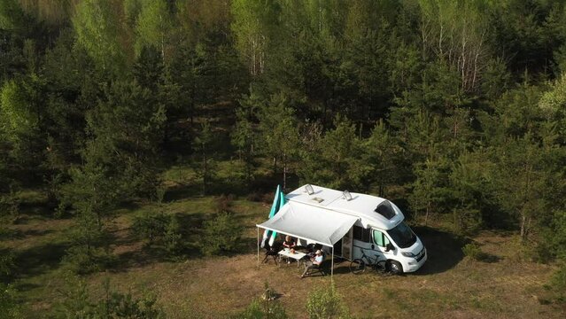 An aerial view of a family holiday near a motorhome in the woods . Travel concept